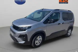 Peugeot Rifter gris en 3/4 avant droit, avec barres de toit et porte latérale visible, jantes alliage 17 pouces.