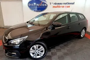 Peugeot 308 noire en break vue 3/4 avant droit dans un showroom avec sol à damier.