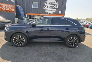 Vue latérale droite du SUV DS7 Crossback E-Tense 225 bleu métallisé avec jantes alliage 19 pouces, stationné devant un garage.