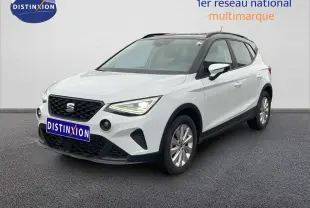 SEAT Arona blanc alpin métal avec toit noir, vue 3/4 avant droit, sur sol gris devant un mur blanc.