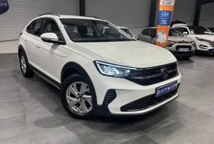 Volkswagen Taigo blanc en 3/4 avant droit, avec jantes alliage et calandre noire brillante en showroom.