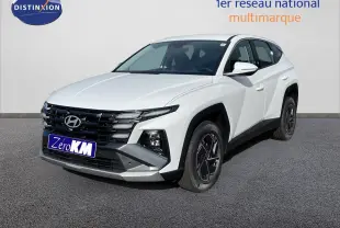 Hyundai Tucson blanc Atlas en 3/4 avant droit, SUV hybride avec calandre noire et jantes bi-ton.