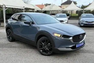 Vue 3/4 avant gauche d'un Mazda CX-30 2024 gris Polymetal avec jantes noires et calandre distinctive.