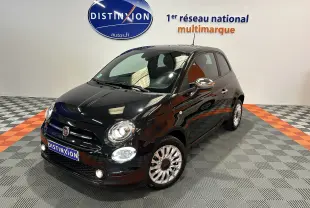 Fiat 500 noire vue 3/4 avant droit dans un showroom avec phares allumés et jantes multibranches.