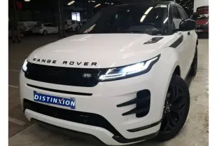 Vue 3/4 avant droite du Range Rover Evoque blanc avec toit noir et jantes noires dans un garage.
