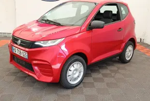 Vue 3/4 avant droit de l'AIXAM Ambition 0.5 City Pack 2024 rouge avec rétroviseur côté conducteur visible.