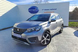 Peugeot 5008 gris en 3/4 avant droit, SUV familial avec jantes alliage et calandre distinctive, stationné en extérieur.