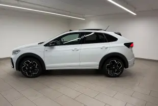 Vue de profil côté gauche d'un Volkswagen Taigo blanc pur avec toit noir et jantes alliage noires en intérieur neutre.