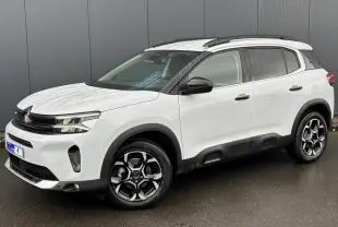 Vue 3/4 avant droite d’un Citroën C5 Aircross blanc Okénite avec jantes alliage bi-ton et barres de toit noires.