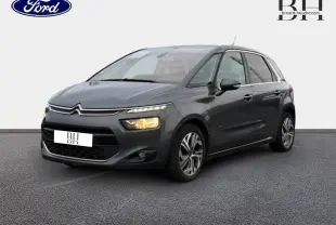 Citroën C4 Picasso gris Shark vue 3/4 avant droit avec phares allumés sur fond neutre.
