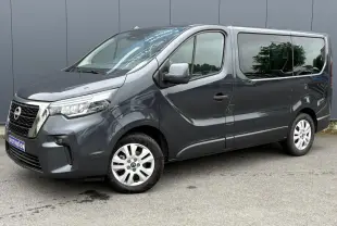 Nissan Primastar gris comète vue 3/4 avant droit, hayon vitré et jantes alliage 17 pouces visibles.