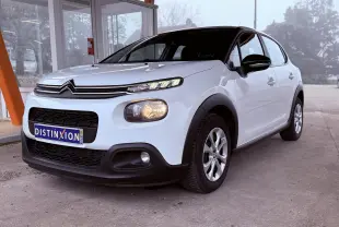 Vue 3/4 avant droite d'une Citroën C3 Société blanche de 2019 avec calandre noire et feux allumés.