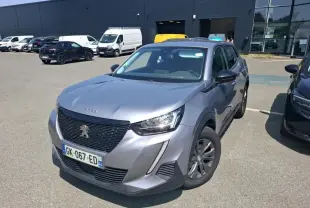 Peugeot 2008 gris Artense vue 3/4 avant droit, avec calandre noire et jantes foncées sur parking extérieur.