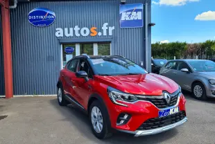 Renault Captur rouge flamme avec toit noir en 3/4 avant droit, stationné devant un bâtiment autos.fr