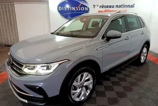 Volkswagen Tiguan gris foncé vu en 3/4 avant droit dans un showroom avec éclairage intérieur.