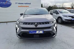 Vue de face d'une Renault Symbioz gris cassiopée avec feux LED allumés sur un parking extérieur.