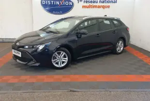 Toyota Corolla hybride bleu vue de profil gauche en stationnement intérieur avec jantes alliage et toit ouvrant.