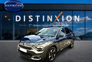 Citroën C4 gris vue 3/4 avant droit, avec jantes alliage et calandre distinctive, devant showroom Distinxion.