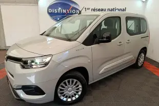 Toyota Proace City Verso électrique gris clair vu en 3/4 avant droit dans un showroom intérieur.
