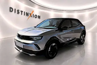 Opel Mokka Electric gris en 3/4 avant droit, toit noir et jantes alu distinctives dans un showroom lumineux.