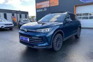 Volkswagen Tiguan 1.5 eHybrid bleu nuit en 3/4 avant droit, avec jantes alliage et calandre moderne sur parking.