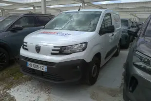Vue 3/4 avant droite d’un Peugeot Partner blanc utilitaire avec logo France Cars sur le capot, stationné entre deux véhicules.