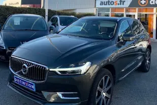 Vue 3/4 avant d'un Volvo XC60 Inscription Luxe marron foncé avec jantes alliage et calandre chromée, stationné en extérieur.