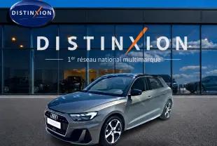Audi A1 Sportback gris chronos vue 3/4 avant droit avec toit noir et jantes alu distinctives devant un showroom Distinxion.