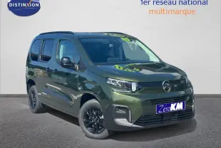 Vue 3/4 avant du Citroën Berlingo 2026 en vert Sirkka Green avec jantes noires et barres de toit visibles.