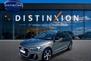 Audi A1 Sportback gris chronos vue 3/4 avant droit devant une vitrine Distinxion, jantes alu et toit noir.