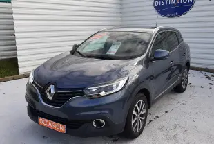 Renault Kadjar gris en 3/4 avant droit, avec phares LED et jantes alliage, stationné devant un mur blanc.