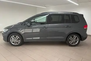 Profil côté gauche d'un Volkswagen Touran gris dauphin 2025, version 7 places avec jantes alliage 17 pouces en intérieur lumineux.
