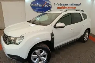 SUV Dacia Duster blanc en 3/4 avant droit, avec barres de toit noires et jantes alliage visibles.