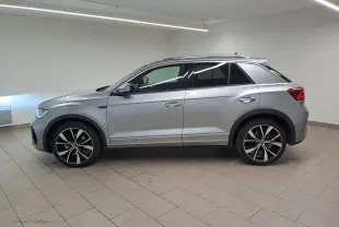 Vue de profil côté gauche d'un Volkswagen T-Roc 2025 gris pyrite avec jantes alliage 19'' noires et feux arrière LED.
