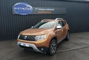 SUV Dacia Duster orange Atacama vu en 3/4 avant droit, avec jantes alliage et barres de toit argentées.