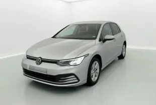 Volkswagen Golf VIII gris reflex vue 3/4 avant droit avec phares allumés dans un studio blanc.