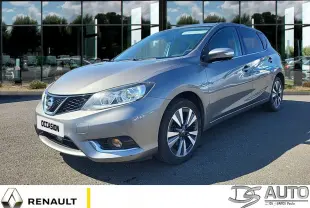 Vue 3/4 avant droit d'une Nissan Pulsar gris métallisé stationnée devant un bâtiment vitré, avec jantes alliage visibles.