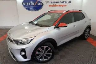 Vue 3/4 avant droit d'un KIA Stonic gris clair avec toit et rétroviseurs orange, roues alliage et barres de toit chromées.