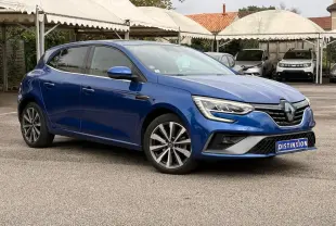 Renault Mégane IV Berline bleu Iron vue 3/4 avant droit, avec jantes alliage et calandre RS Line distinctive.