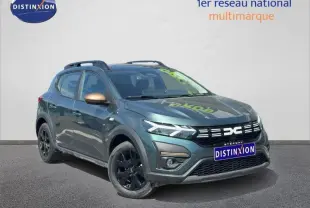 Vue 3/4 avant droite d'une Dacia Sandero Stepway 2025 vert cèdre métallisé avec jantes noires et barres de toit.
