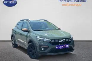 Vue 3/4 avant droite d'une Dacia Sandero Stepway 2025 vert cèdre métallisé avec jantes noires et barres de toit.