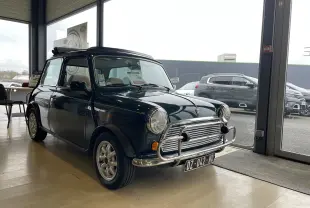 Vue 3/4 avant gauche d'une MINI 1.3 i British Open 1995 en British Racing Green avec pare-chocs chromé intérieur showroom.