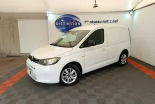 Vue 3/4 avant droit d'un Volkswagen Caddy blanc 2022 avec jantes alliage et rétroviseurs noirs dans un garage.