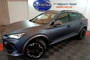 CUPRA Formentor gris foncé en 3/4 avant droit, avec jantes noires et phares LED allumés en intérieur showroom.
