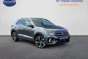 Volkswagen T-Roc gris Indium métallisé en 3/4 avant droit, avec jantes alliage et barres de toit visibles.