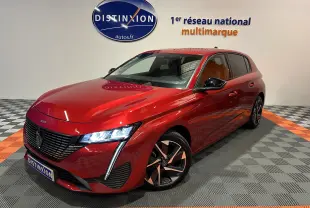 Peugeot 308 rouge vue 3/4 avant droit avec phares allumés et jantes alliage bicolores dans showroom.