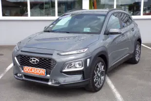 Hyundai Kona gris métal en 3/4 avant droit, avec calandre noire et jantes alliage bi-ton visibles.