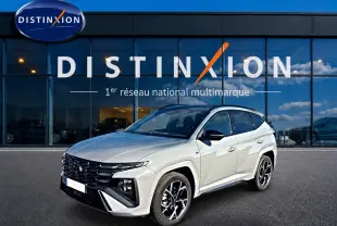 Vue 3/4 avant droite d'un Hyundai Tucson 2026 gris shadow avec jantes alu et calandre noire devant un showroom Distinxion.