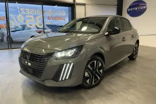 Peugeot 208 gris selenium vue 3/4 avant en intérieur, avec calandre noire et feux LED distinctifs allumés.