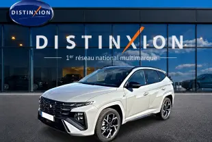 Hyundai Tucson 2026 blanc en 3/4 avant droit avec calandre noire et jantes alliage devant showroom Distinxion.